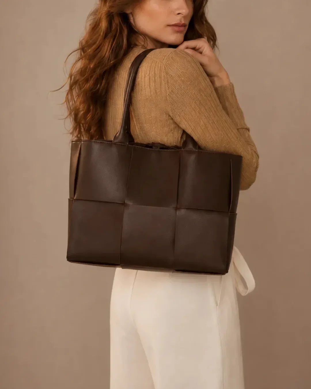 Model carrying the Florence woven leather tote bag in dark chocolate leather over the shoulder.