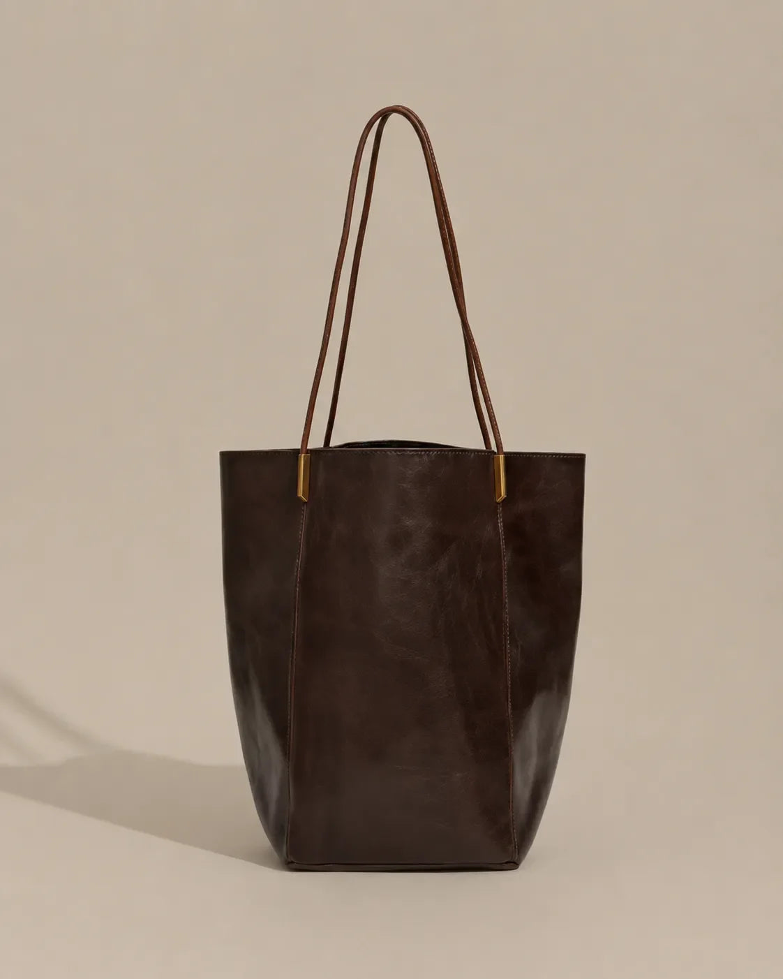 Angled front view of the Margot Tote in dark chocolate genuine leather, highlighting its elegant proportions, refined silhouette and minimalist aesthetic.