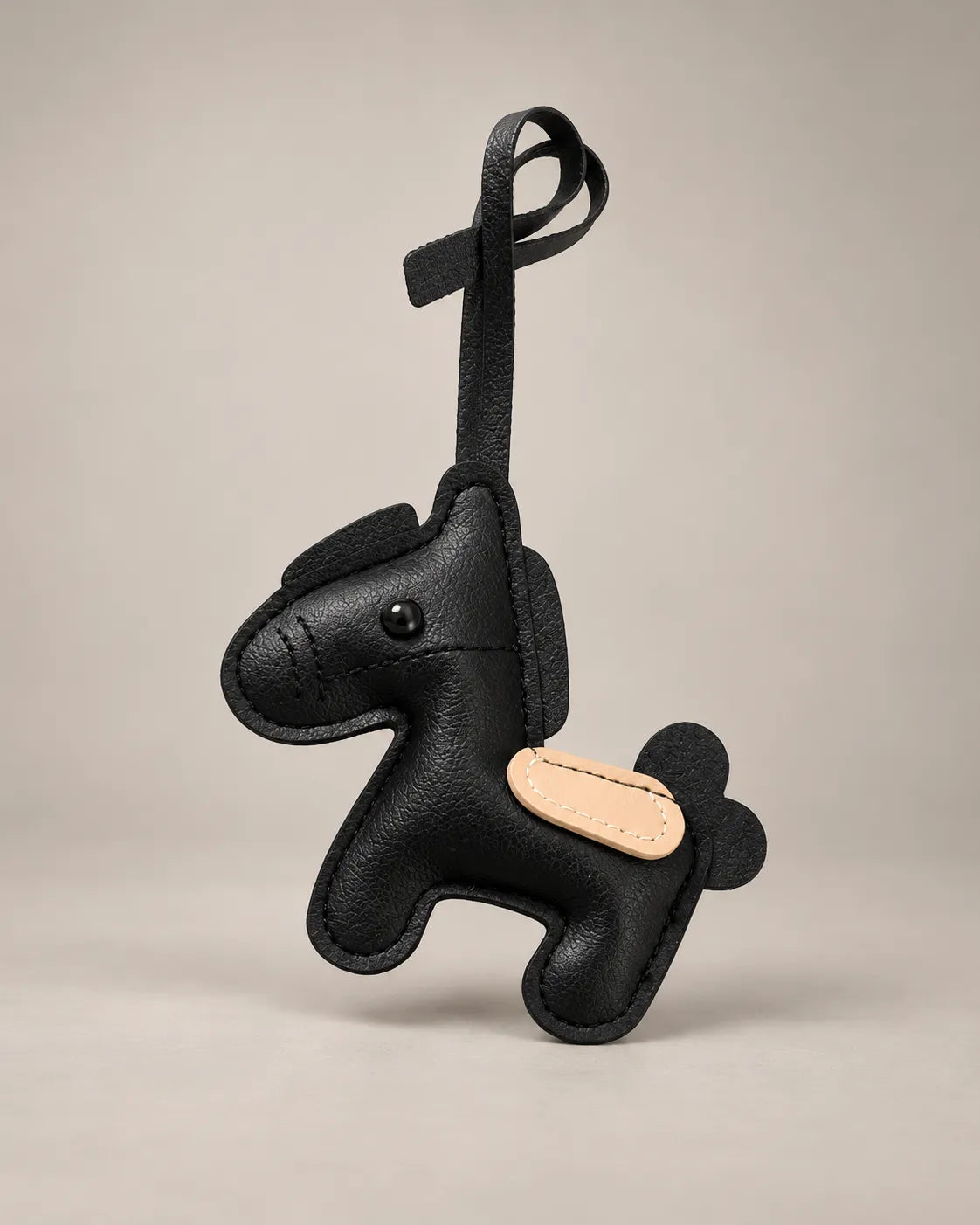 Pony bag charm in black PU leather with a black mane and tail, tan saddle patch and a hanging strap, by Malena London