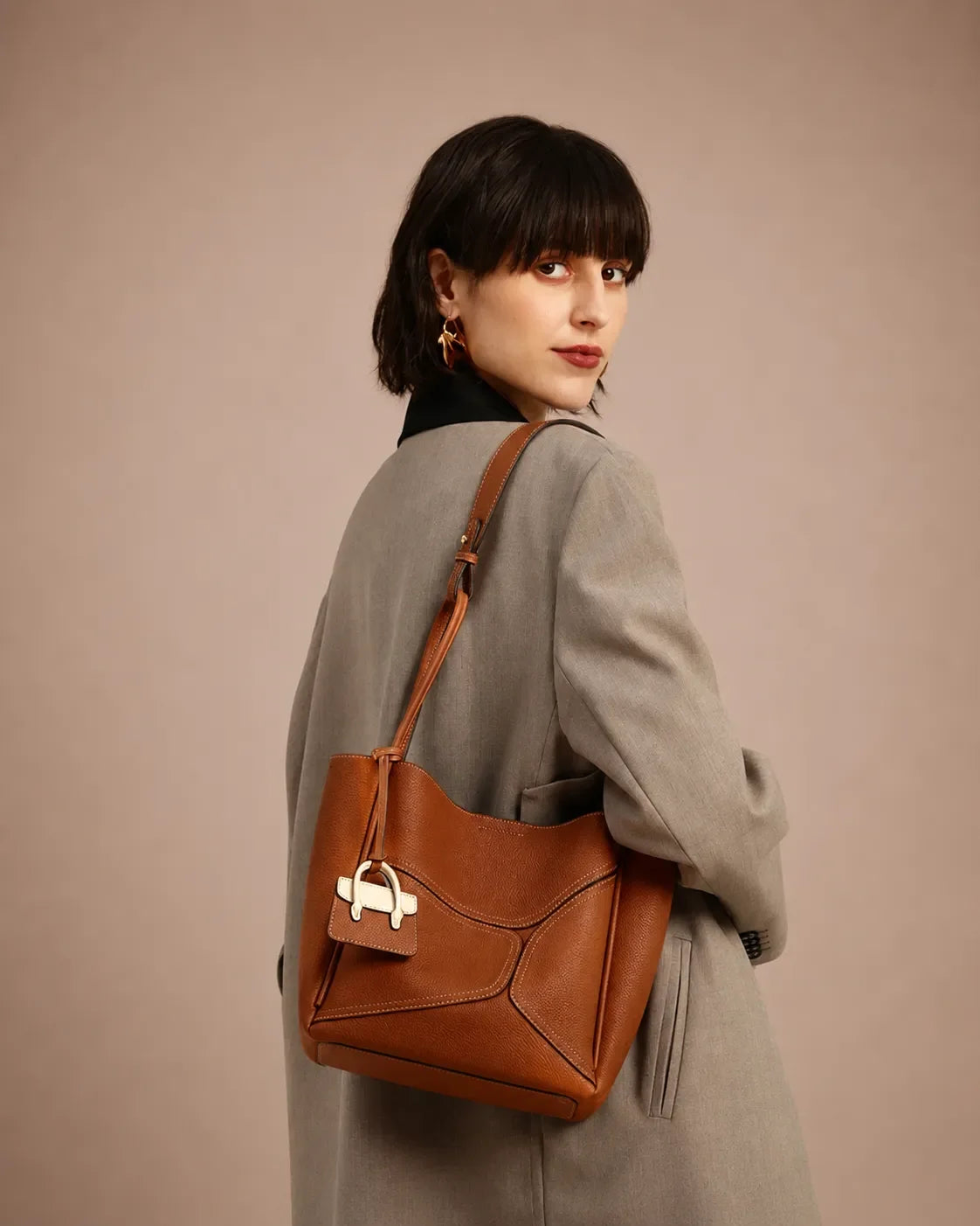 Woman styling The Delphine cookie luxury leather handbag with tailored outerwear. Premium women's leather handbag crafted for modern workdays, city dressing and quiet luxury style.