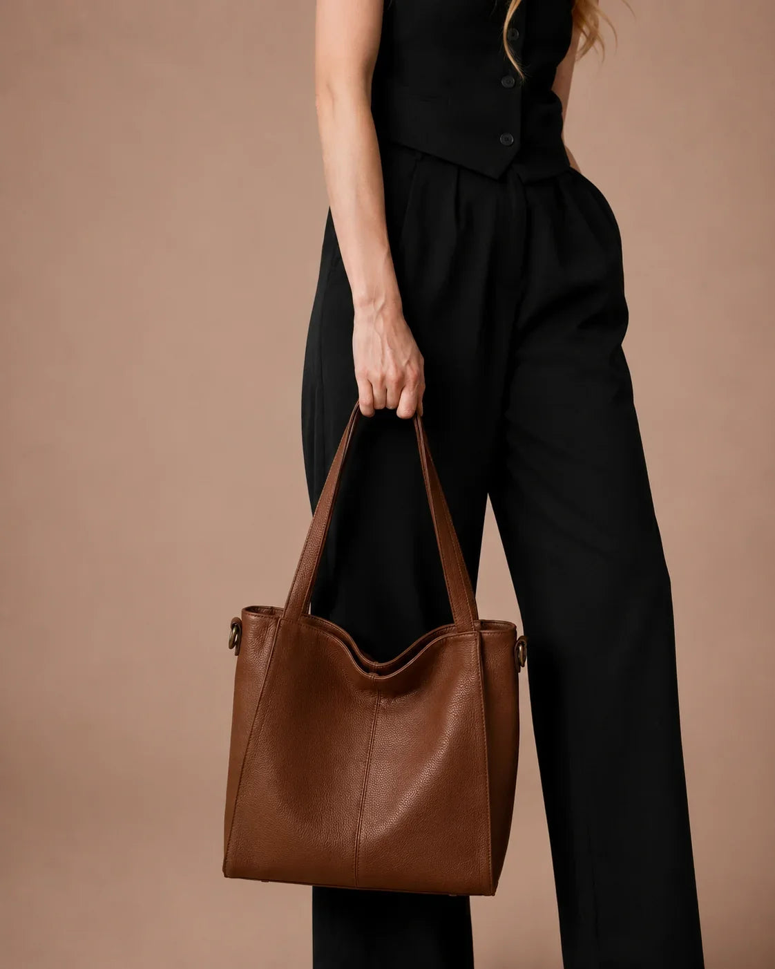 Woman carrying the Eleanor genuine leather work tote bag in Brown. Spacious women's leather handbag with structured silhouette, premium first-layer cowhide leather and elegant design for work, commuting and everyday use.