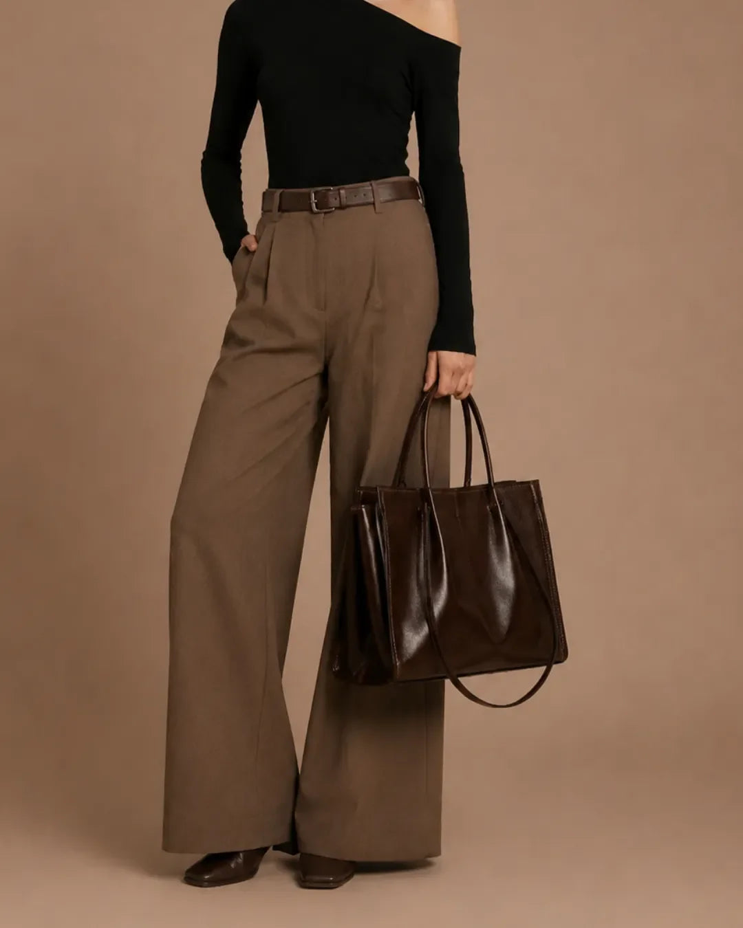 Model holding The Edith dark chocolate genuine leather tote bag, featuring a refined structured silhouette, spacious interior and elegant everyday style for work, commuting and city living.