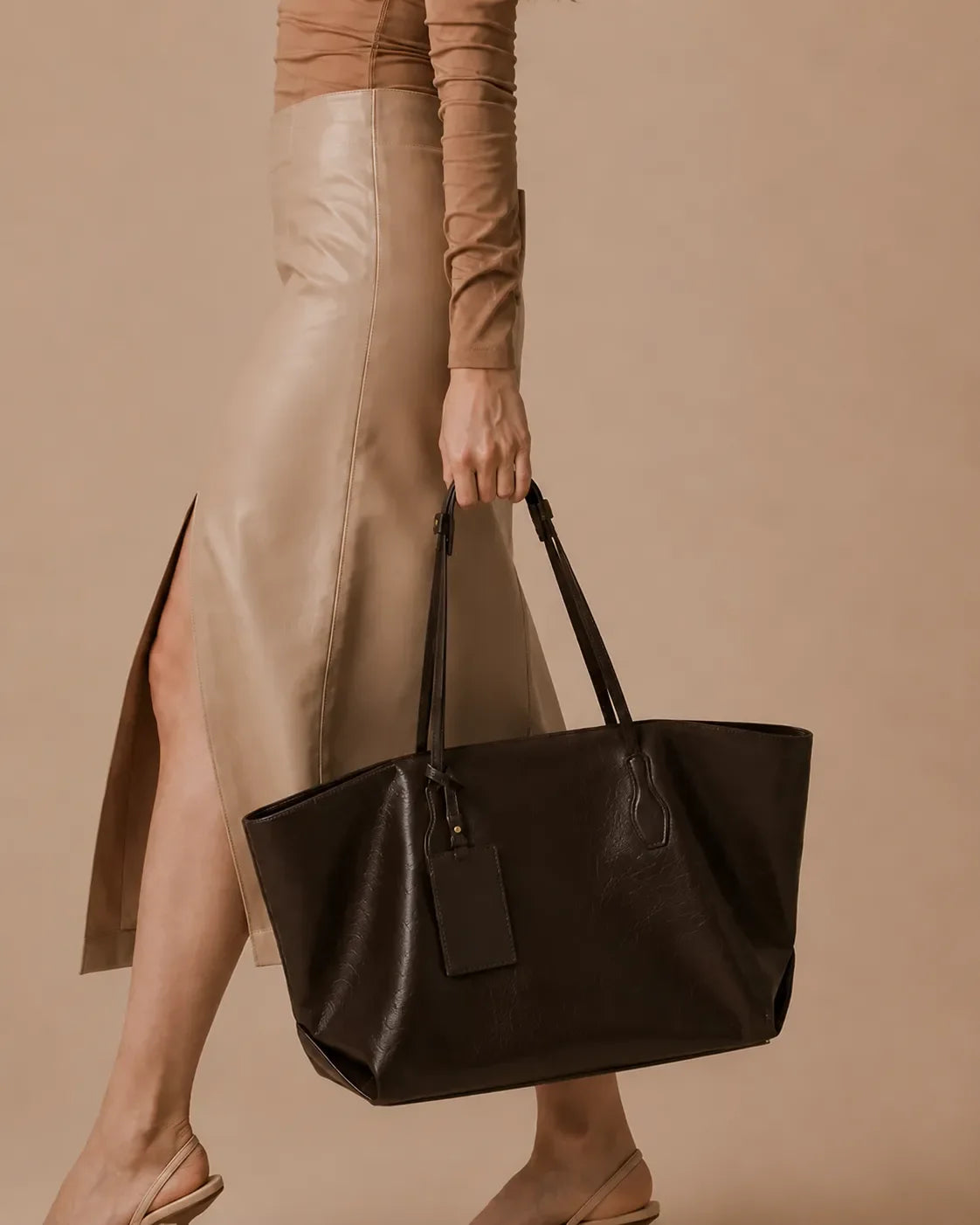 Model walking with The Emilia dark chocolate genuine leather tote bag, highlighting its comfortable shoulder straps, premium leather construction and refined everyday style for modern women.