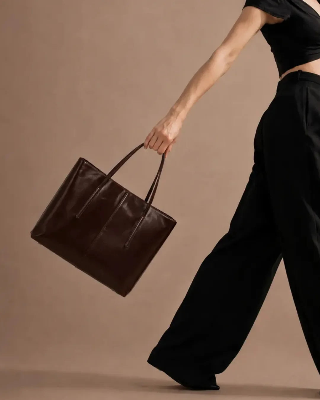 Model walking with The Margaux dark chocolate genuine leather tote bag, showcasing its spacious structured silhouette, premium leather finish and timeless design for work, commuting and everyday elegance.