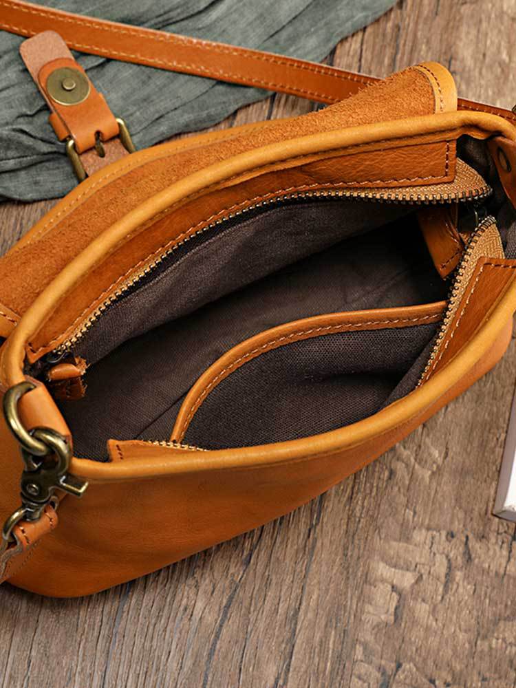Open top zip of the vintage genuine leather shoulder bag in tan showing the dark lining, an inner pocket and a brass-tone strap clip, by Malena London