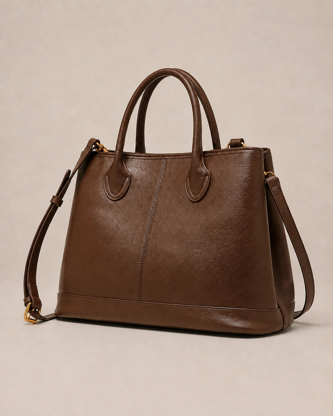Angled view of the Odile large structured genuine leather tote bag in brown showing the panelled silhouette and gold-tone hardware.