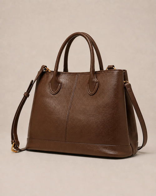 Angled view of the Odile large structured genuine leather tote bag in brown showing the panelled silhouette and gold-tone hardware.