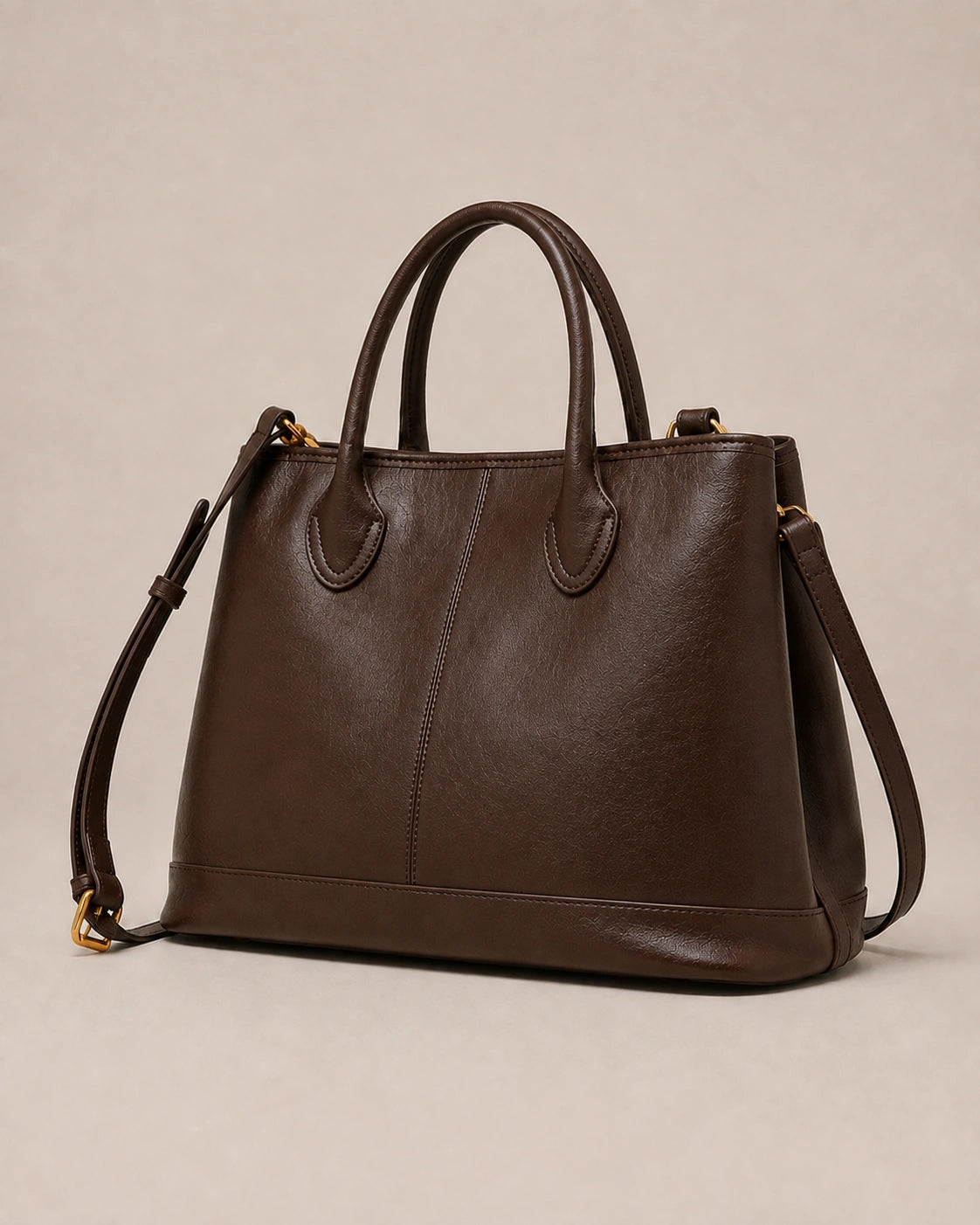 Angled view of the Odile large structured genuine leather tote bag in chocolate showing the panelled silhouette and gold-tone hardware.