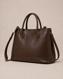 Angled view of the Odile large structured genuine leather tote bag in chocolate showing the panelled silhouette and gold-tone hardware.