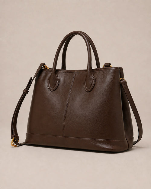 Angled view of the Odile large structured genuine leather tote bag in chocolate showing the panelled silhouette and gold-tone hardware.