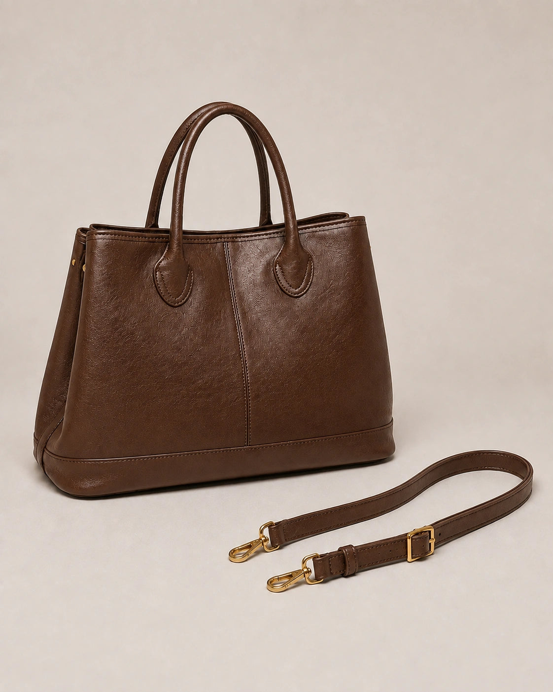 Angled view of the Odile large structured genuine leather tote bag in brown with the crossbody strap laid out.