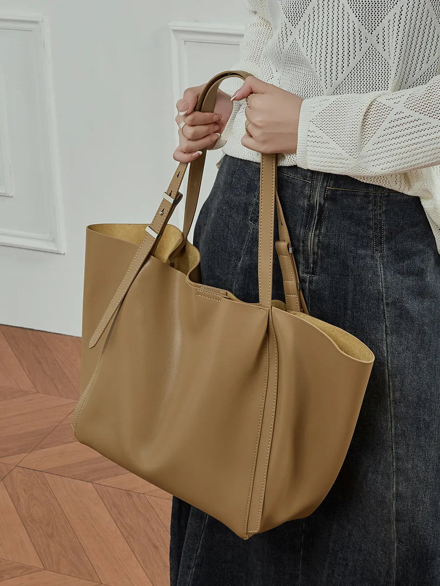 Woman holding the Rosalind oversized genuine leather tote bag in brown by the handles.