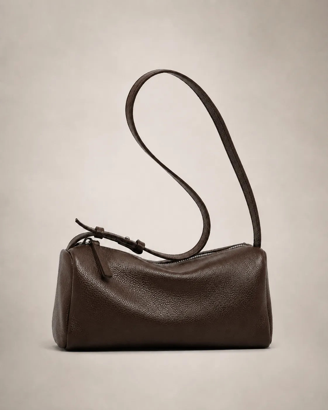 Side view of the Simone genuine leather cylindrical crossbody bag in brown showing the barrel silhouette and adjustable strap.