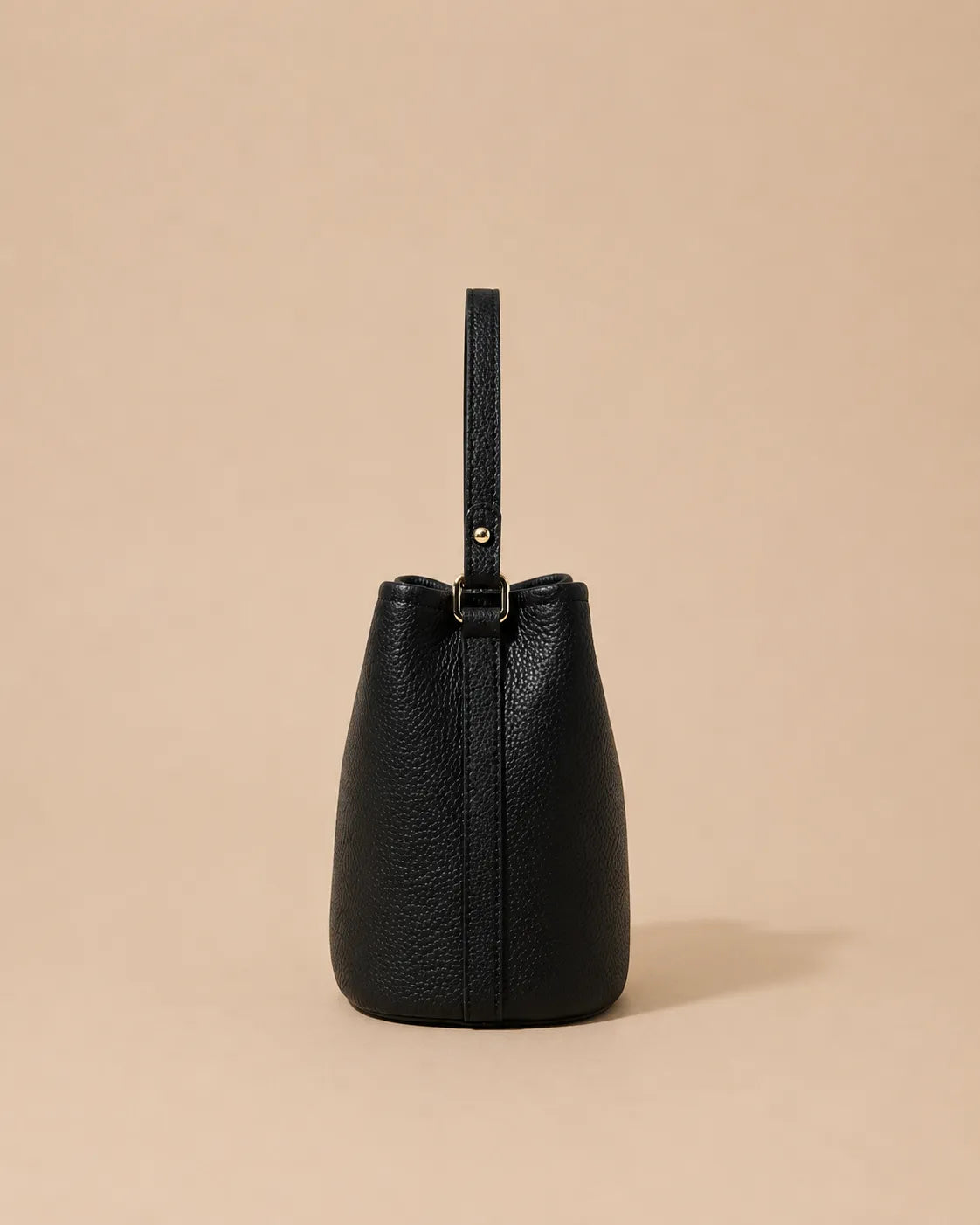 Side view of the Bonnie genuine leather bucket bag in Black showcasing its compact bucket shape, soft structure and adjustable leather strap