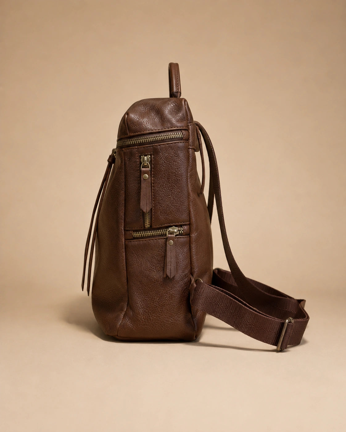 Adeline leather backpack shown holding a phone, wallet and book.
