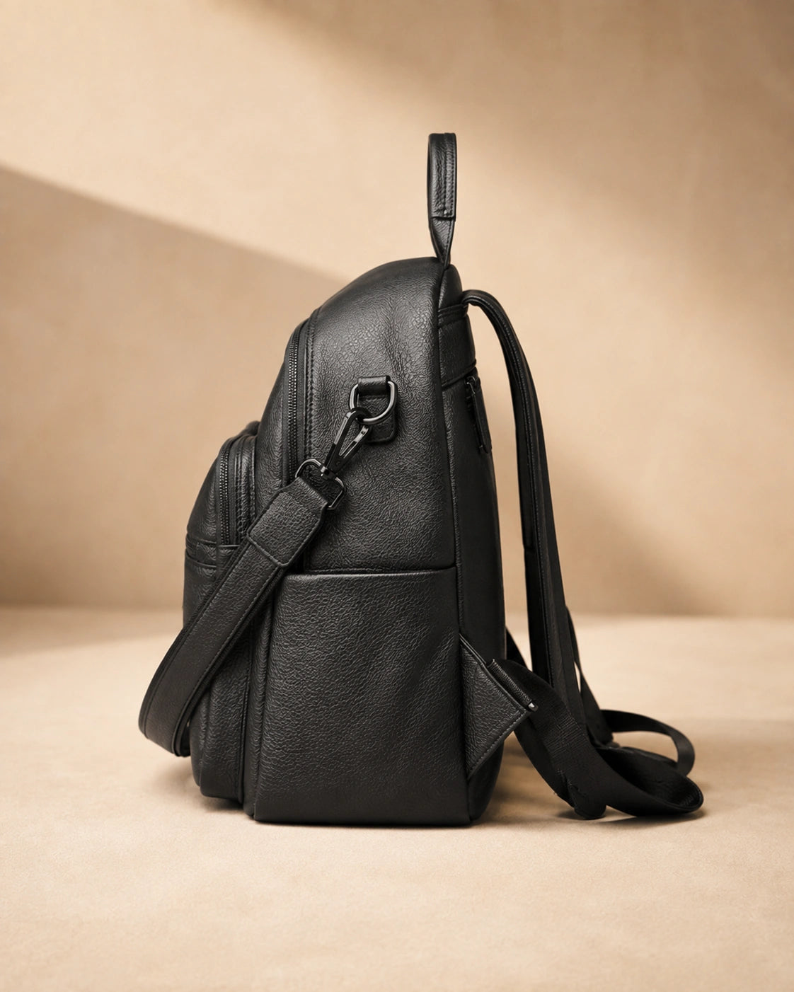 Side view of the Isla lightweight genuine leather travel backpack in black showing the zip pocket and top handle