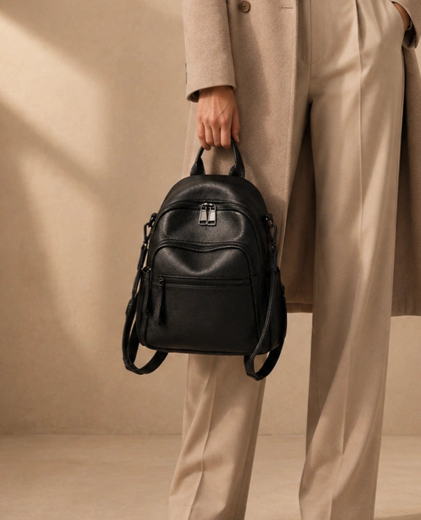 Woman carrying the Isla lightweight genuine leather travel backpack in black by the top handle