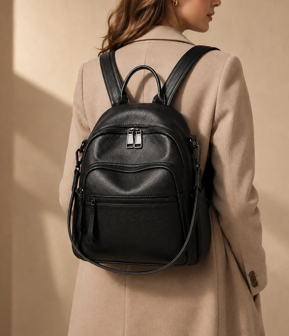 Woman wearing the Isla lightweight genuine leather travel backpack in black, back view