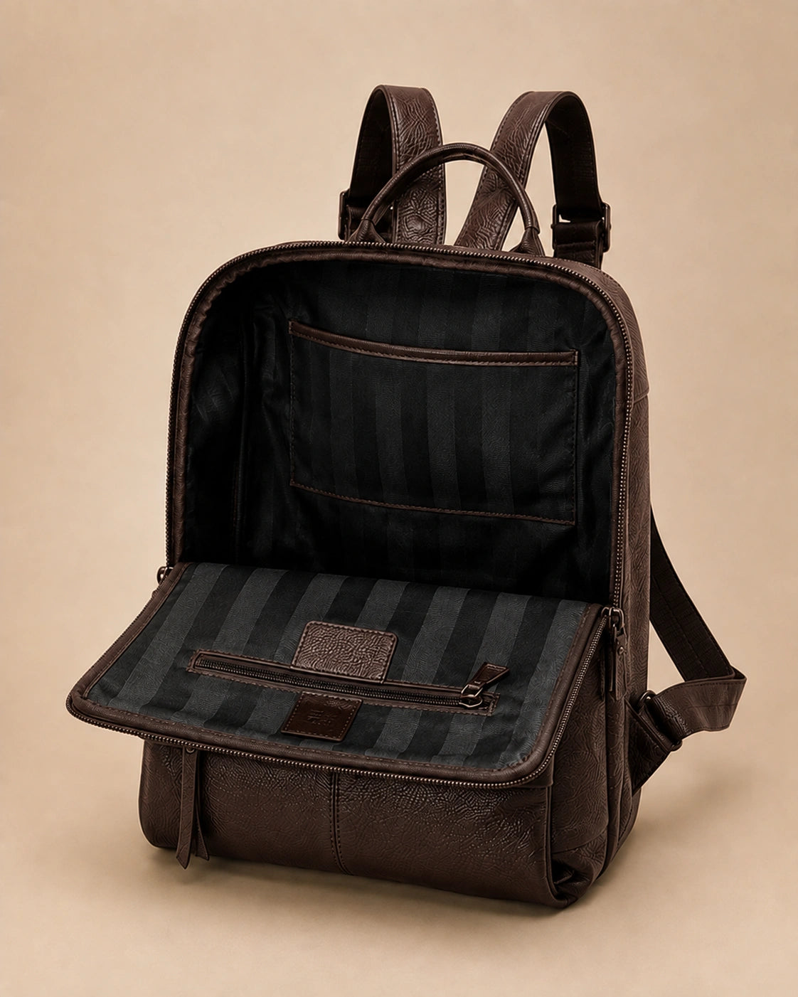 Front pocket detail of the Cecily genuine leather backpack in brown showing the laptop pocket open
