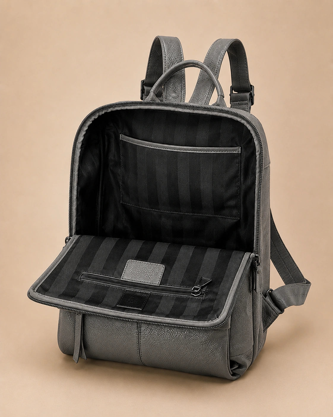 Front pocket detail of the Cecily genuine leather backpack in grey showing the laptop pocket open