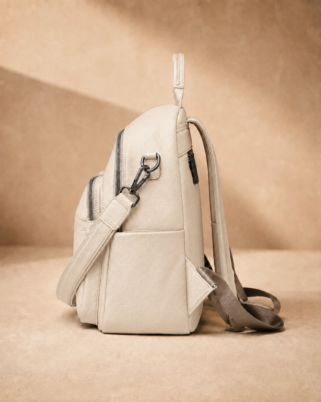 Side view of the Isla lightweight genuine leather travel backpack in off-white showing the zip pocket and top handle