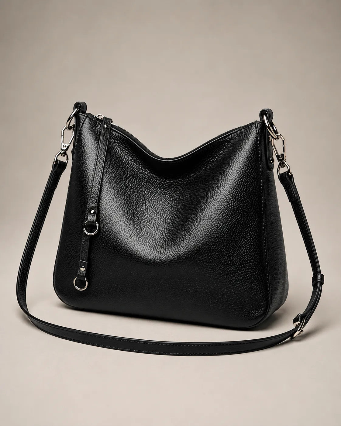 Angled view of the Noémie soft genuine leather hobo shoulder bag in black showing the detachable strap hardware.