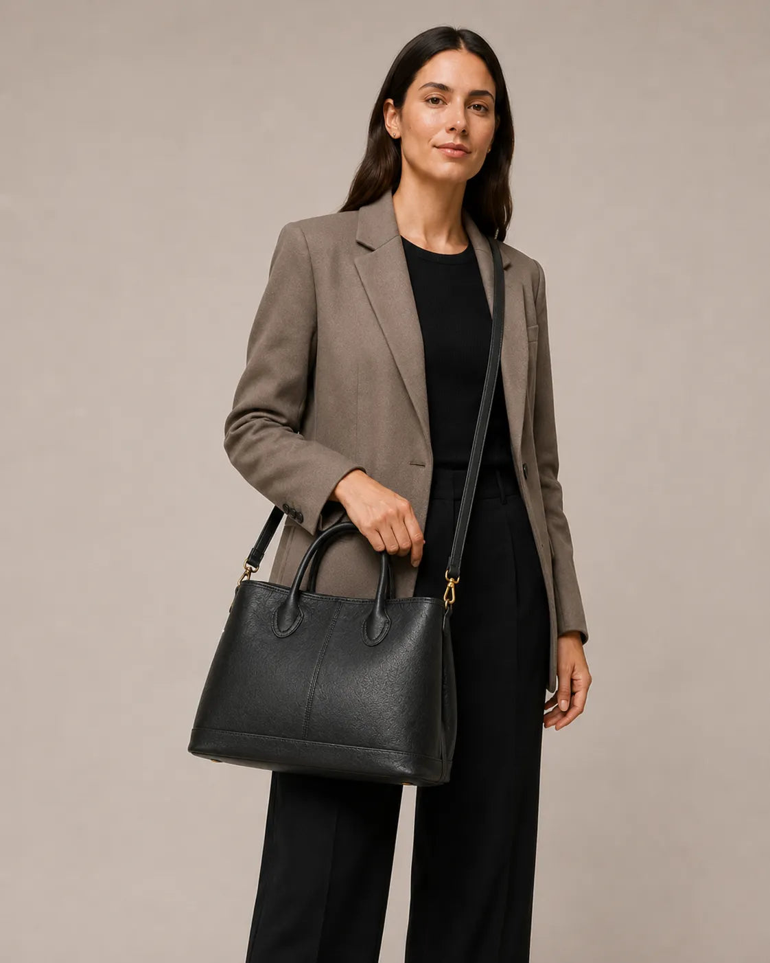 Woman wearing the Odile large structured genuine leather tote bag in black with the crossbody strap.