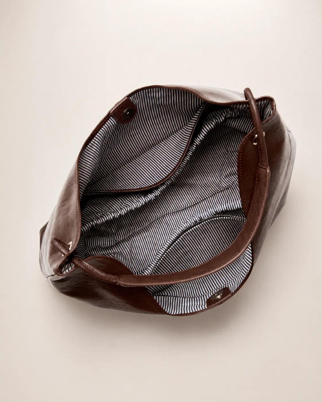 Interior view of the Colette dark chocolate leather hobo tote bag featuring a spacious compartment, striped lining and practical storage pockets.