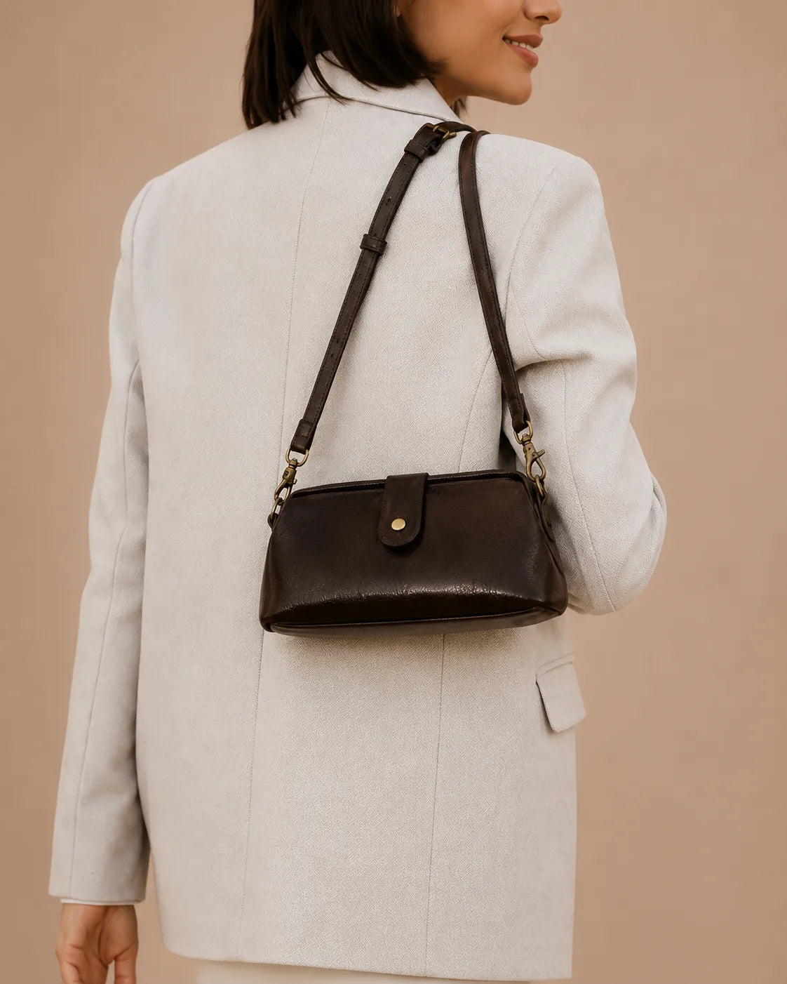 Model carrying the Eloise leather crossbody bag in dark chocolate genuine leather over the shoulder with an elegant day-to-evening outfit.