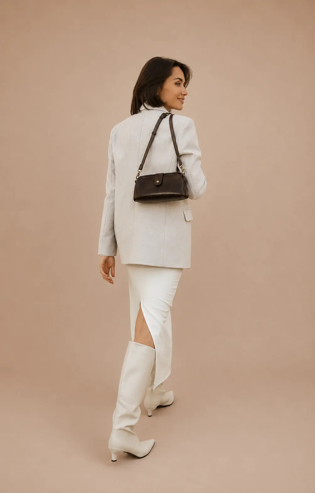 Model carrying the Eloise leather crossbody bag in dark chocolate genuine leather over the shoulder with an elegant day-to-evening outfit.