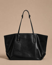 Front view of the Emilia Tote in black leather, featuring a spacious silhouette, adjustable shoulder straps and minimalist design.