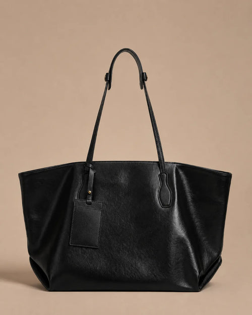 Front view of the Emilia Tote in black leather, featuring a spacious silhouette, adjustable shoulder straps and minimalist design.