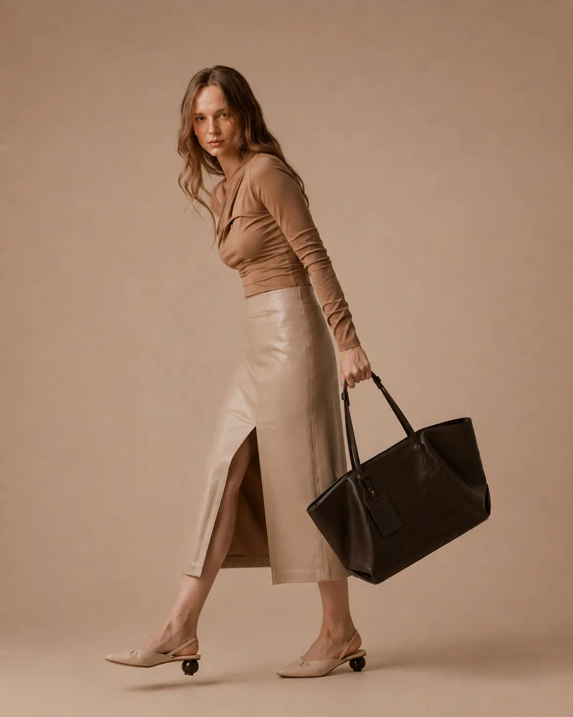 Woman carrying the Emilia Tote in dark chocolate leather, showcasing its soft structured silhouette and versatile everyday styling.