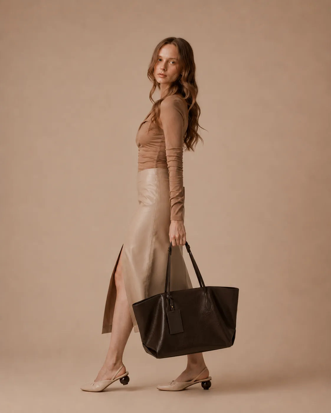 Woman carrying the Emilia Tote leather tote bag styled with a neutral outfit, highlighting its elegant proportions and daily versatility.