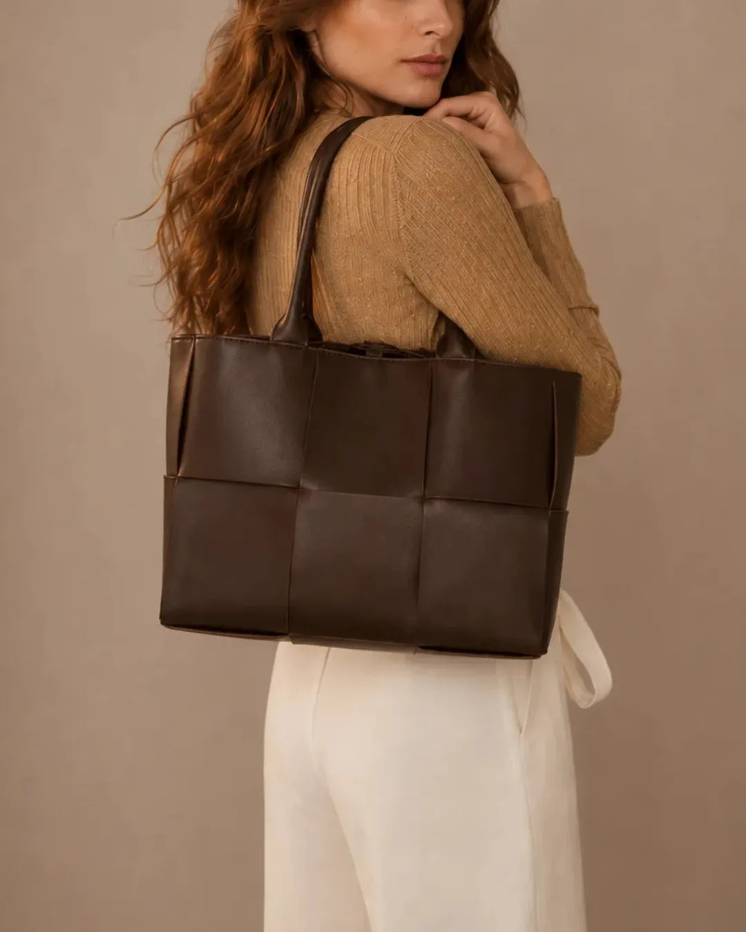 Model carrying the Florence woven leather tote bag in dark chocolate leather over the shoulder.