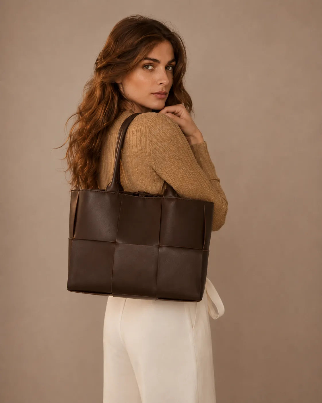 Model carrying the Florence woven leather tote bag in dark chocolate leather over the shoulder.