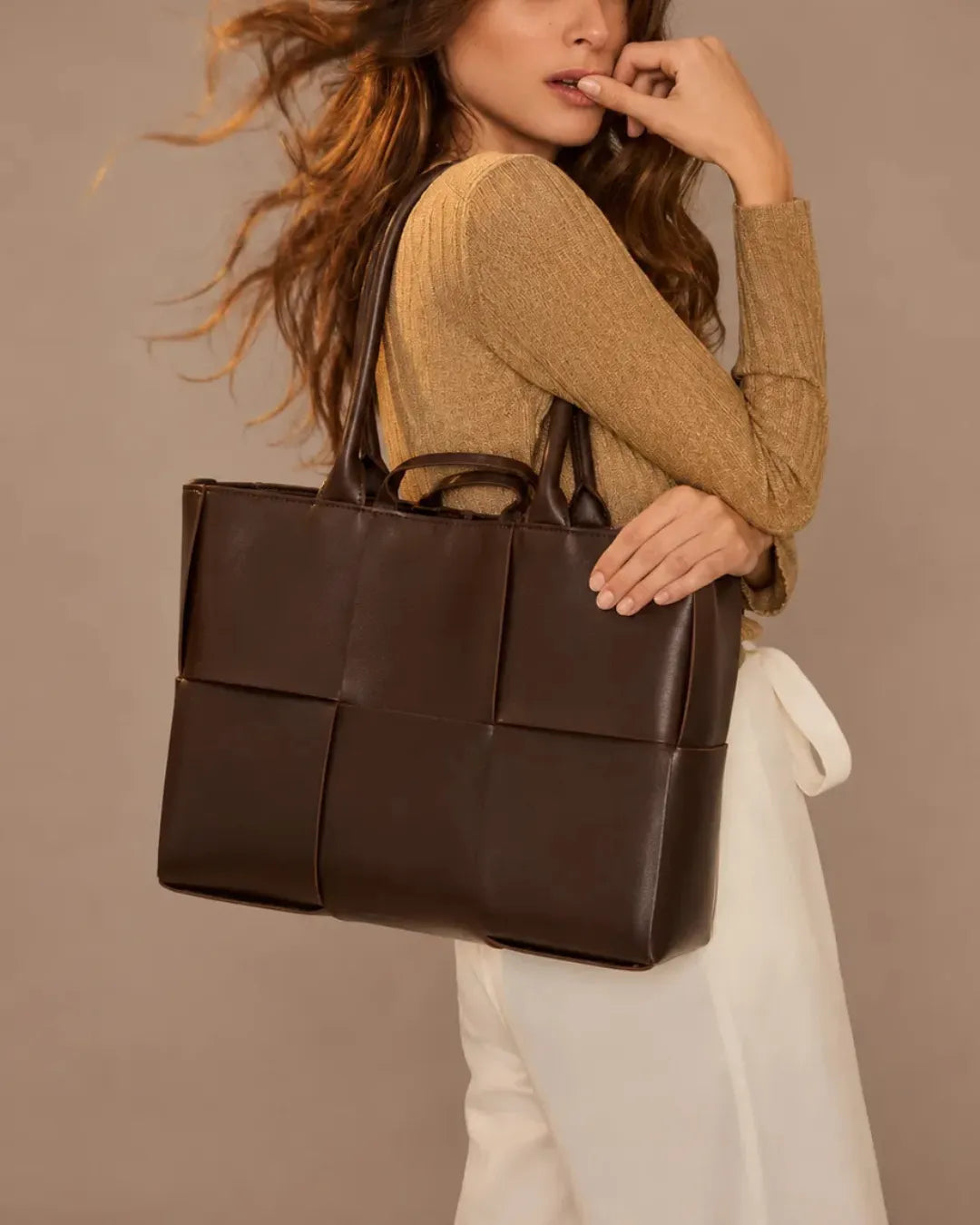 Woman wearing the Florence woven leather tote bag over the shoulder in chocolate brown genuine leather.