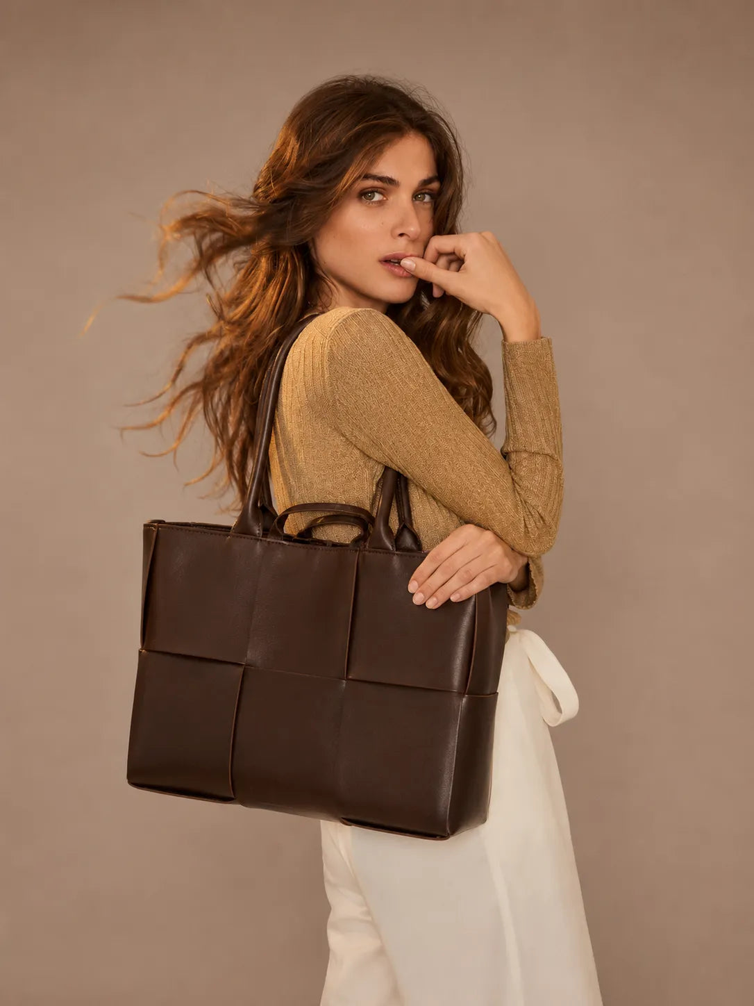 Woman wearing the Florence woven leather tote bag over the shoulder in chocolate brown genuine leather.