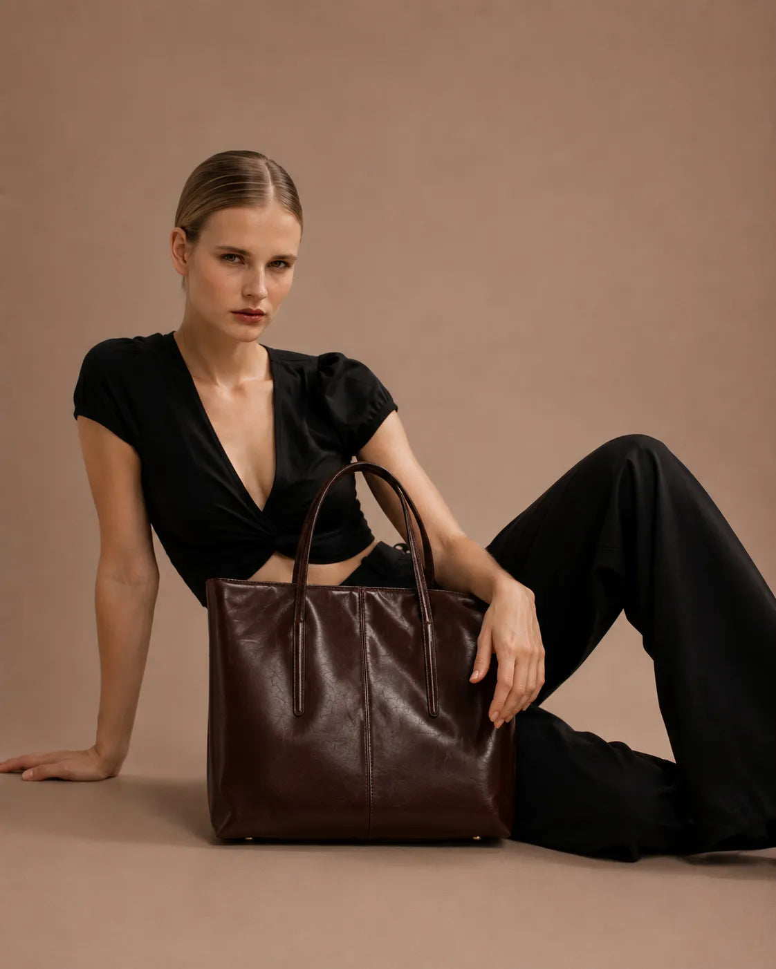 Model seated with the Margaux large dark chocolate leather tote bag showcasing its elegant work-ready design