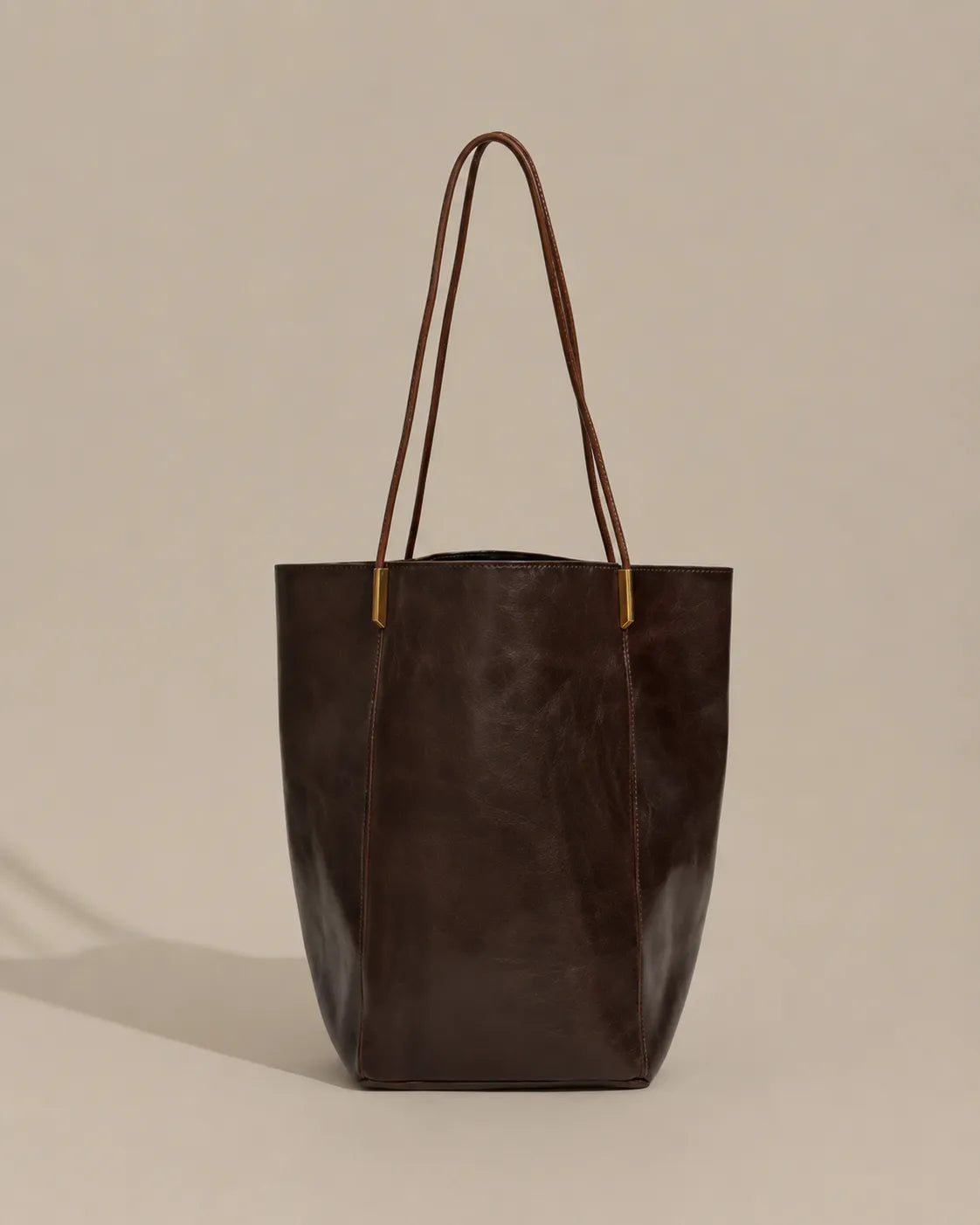 Angled front view of the Margot Tote in dark chocolate genuine leather, highlighting its elegant proportions, refined silhouette and minimalist aesthetic.