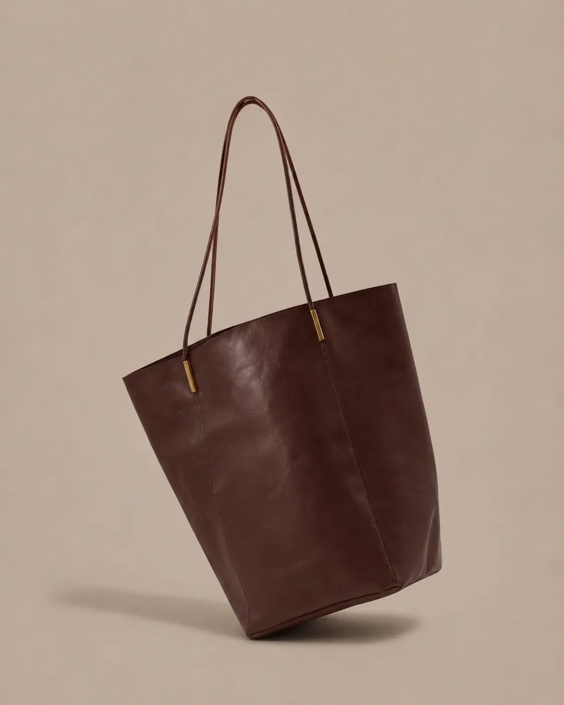 Angled view of the Margot Tote in brown genuine leather, highlighting its minimalist structure and refined craftsmanship.