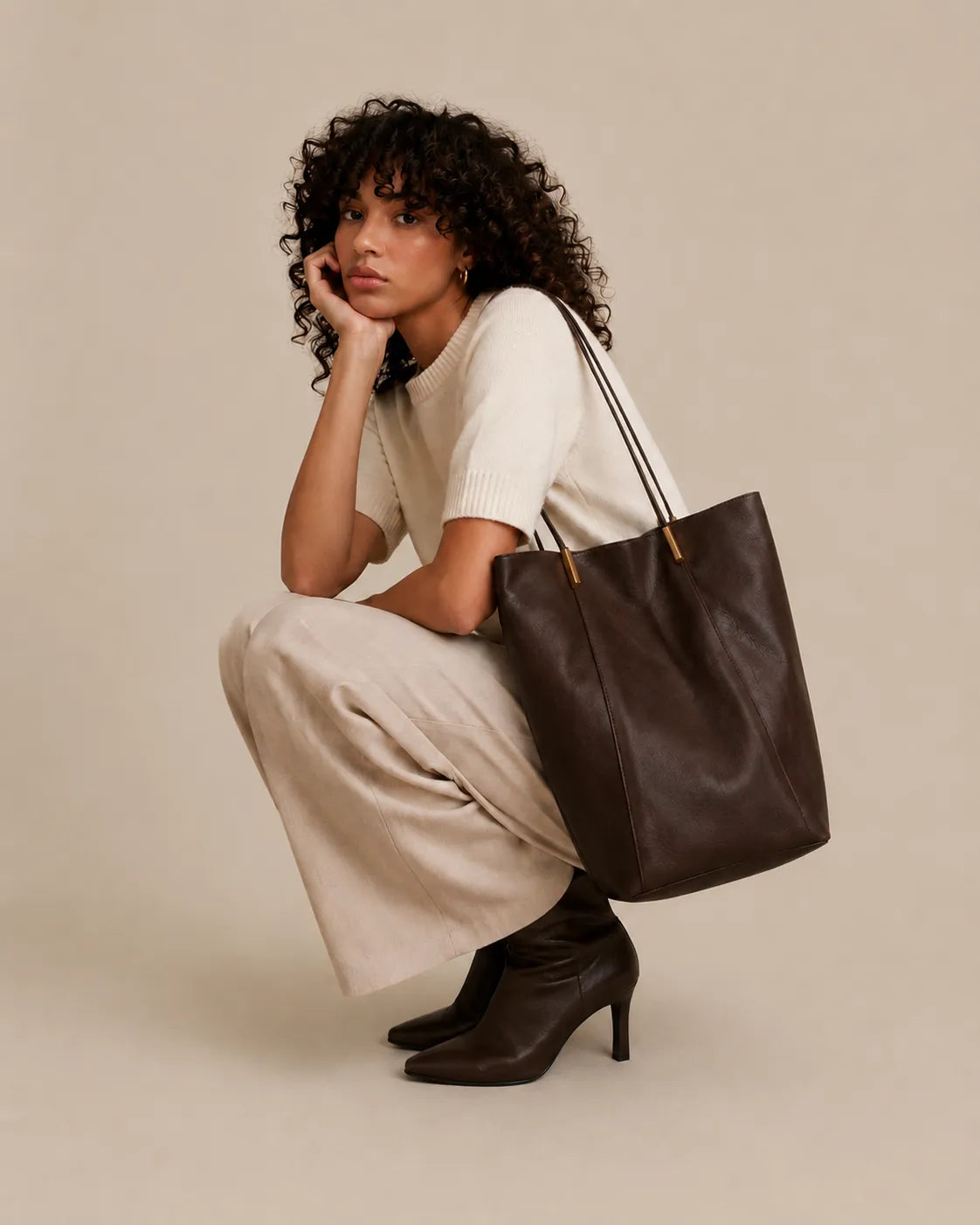 Woman seated with the Margot Tote in dark chocolate genuine leather, showcasing its elegant proportions and refined everyday style.