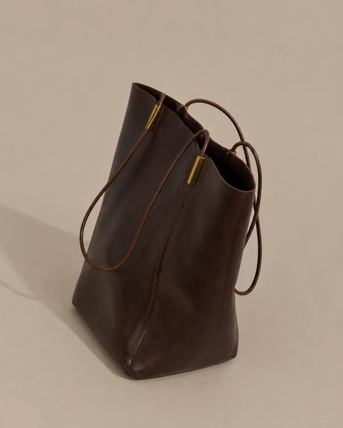 Side view of the Margot Tote in dark chocolate genuine leather, featuring a softly structured shape and slim shoulder straps for everyday wear.