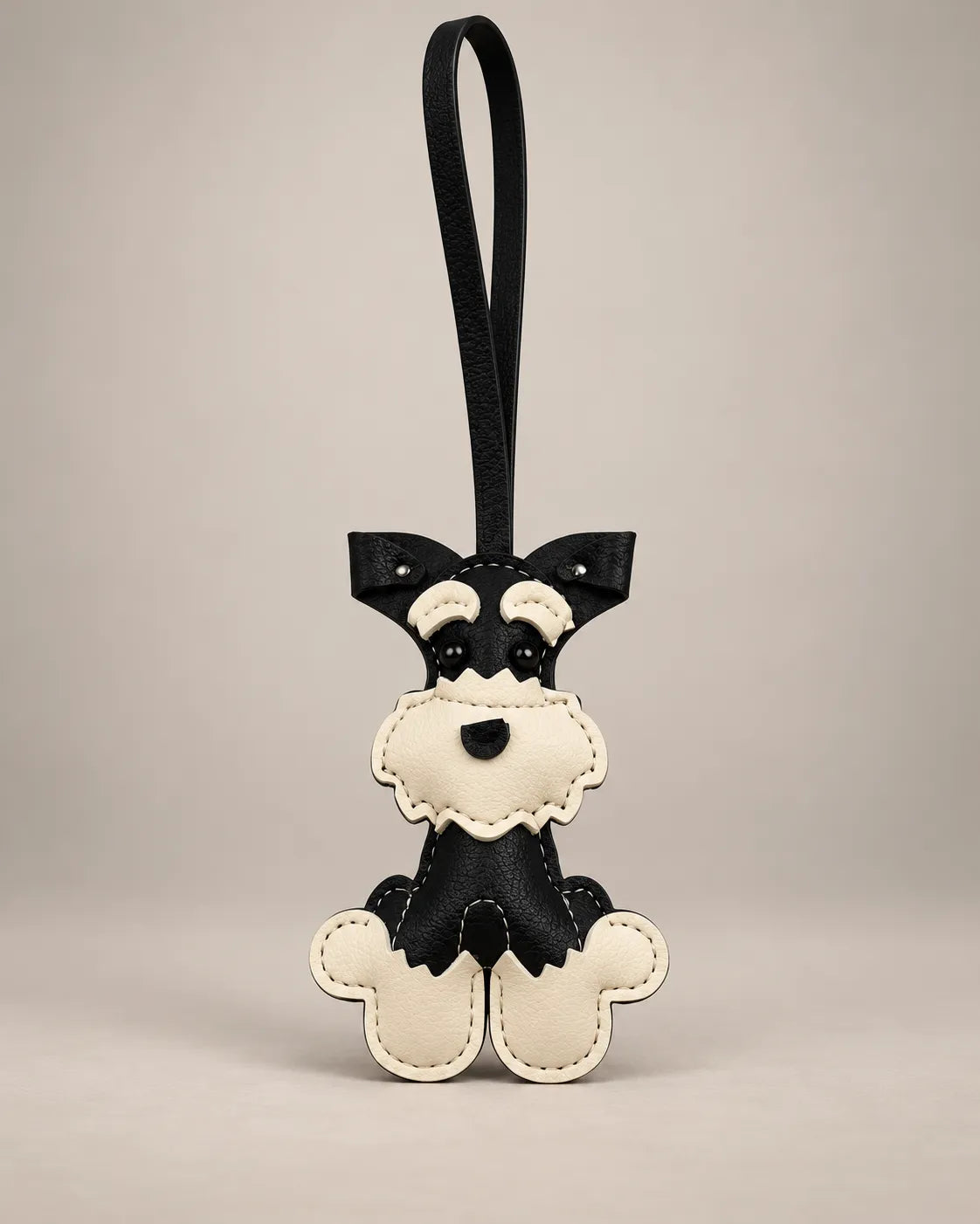 Schnauzer dog bag charm in black PU leather with a cream face and paws, stitched details and a hanging loop strap, by Malena London