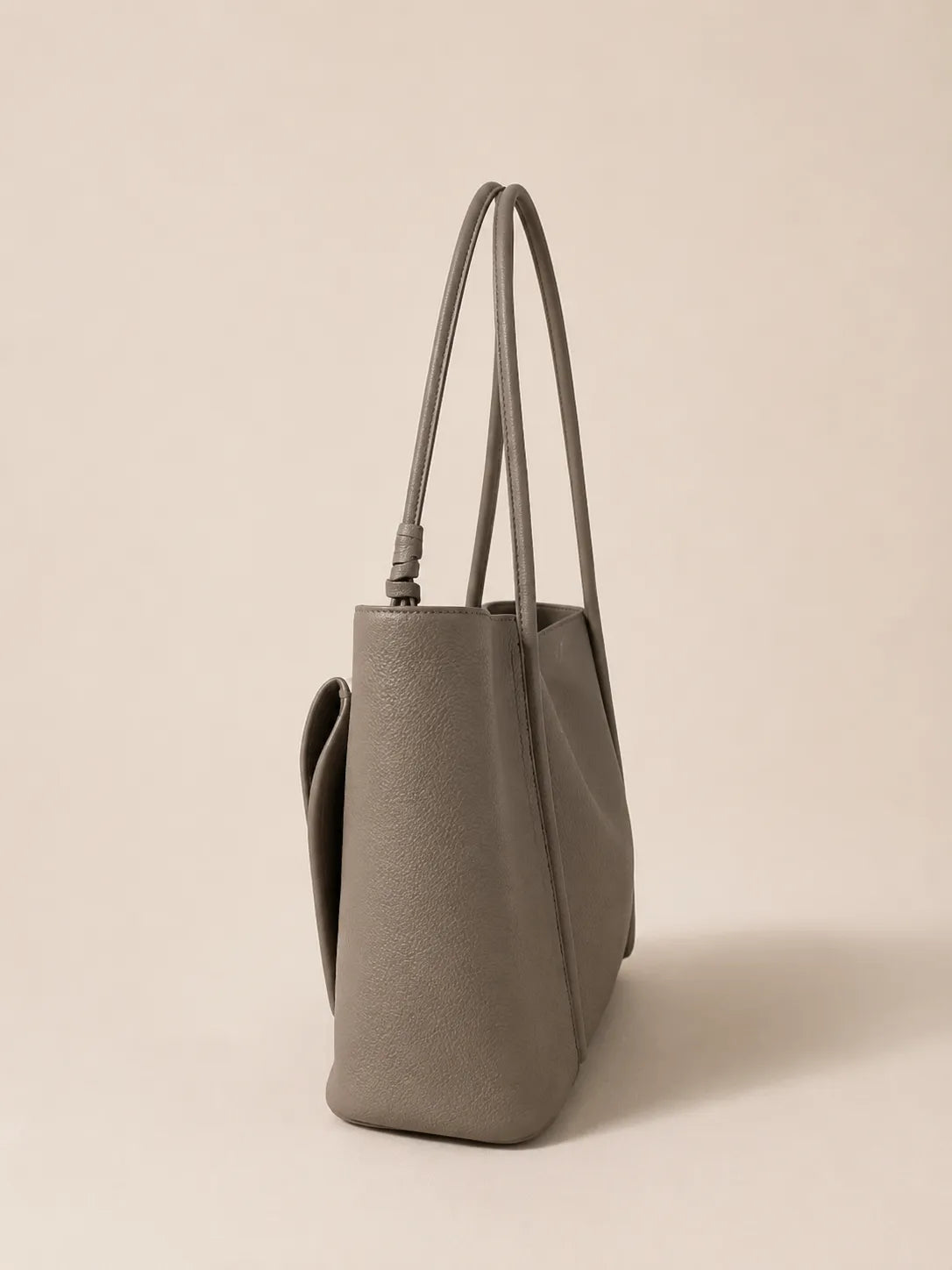 Side view of the Vivienne large Togo leather tote bag in elephant grey showcasing its spacious profile and structured shape
