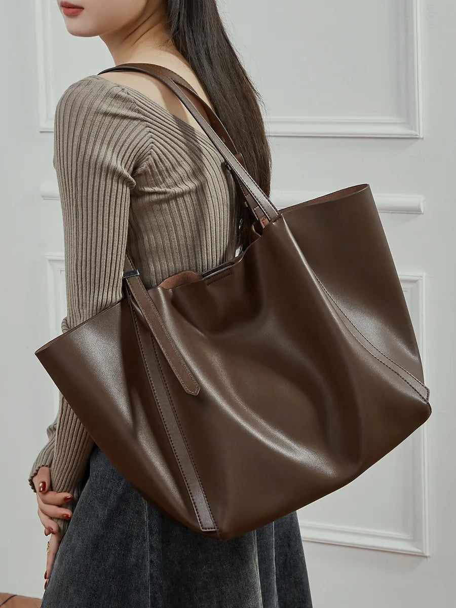 Woman wearing the Rosalind oversized genuine leather tote bag in coffee on the shoulder, close view.