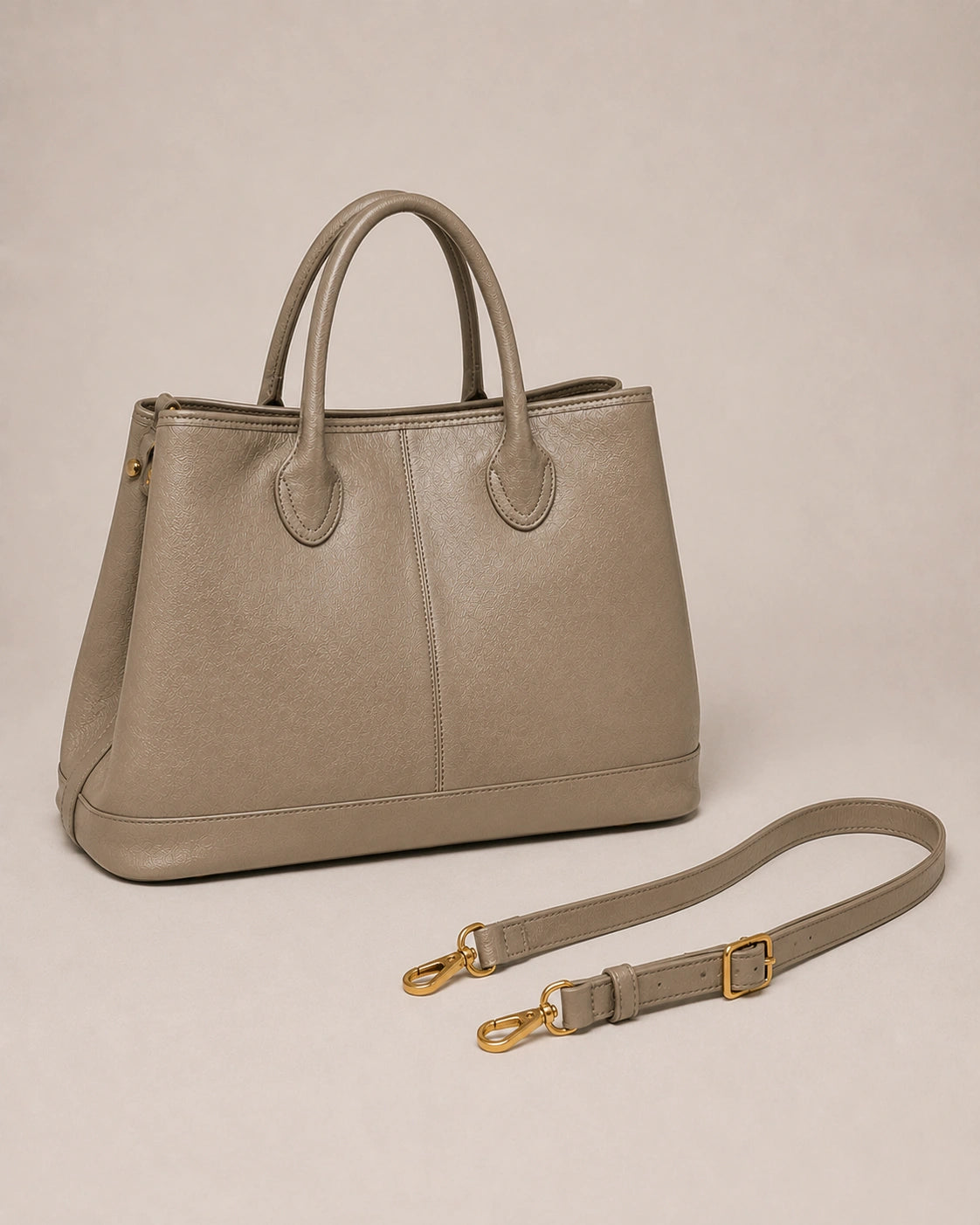 Angled view of the Odile large structured genuine leather tote bag in grey showing the panelled silhouette and gold-tone hardware.