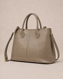 Angled view of the Odile large structured genuine leather tote bag in grey with the crossbody strap laid out.