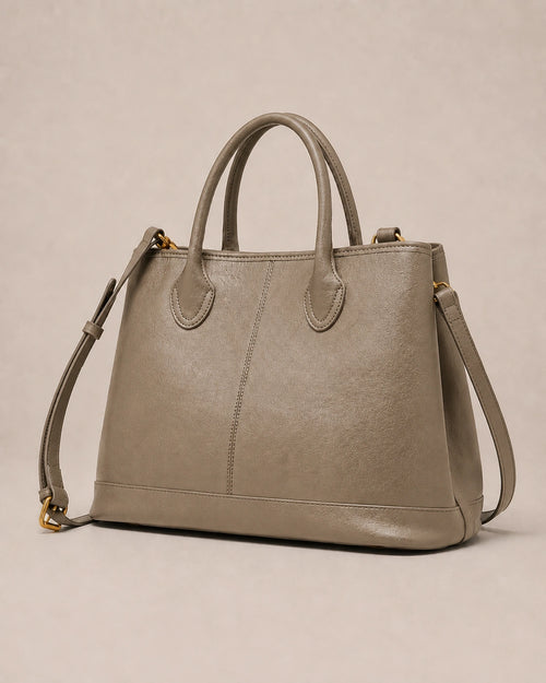 Angled view of the Odile large structured genuine leather tote bag in grey with the crossbody strap laid out.