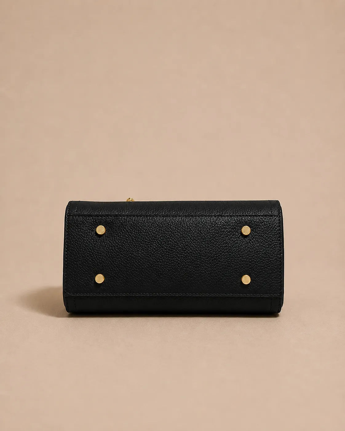 Bottom view of the Beatrice genuine leather top handle bag in black showcasing protective metal feet and structured base for enhanced durability and stability.